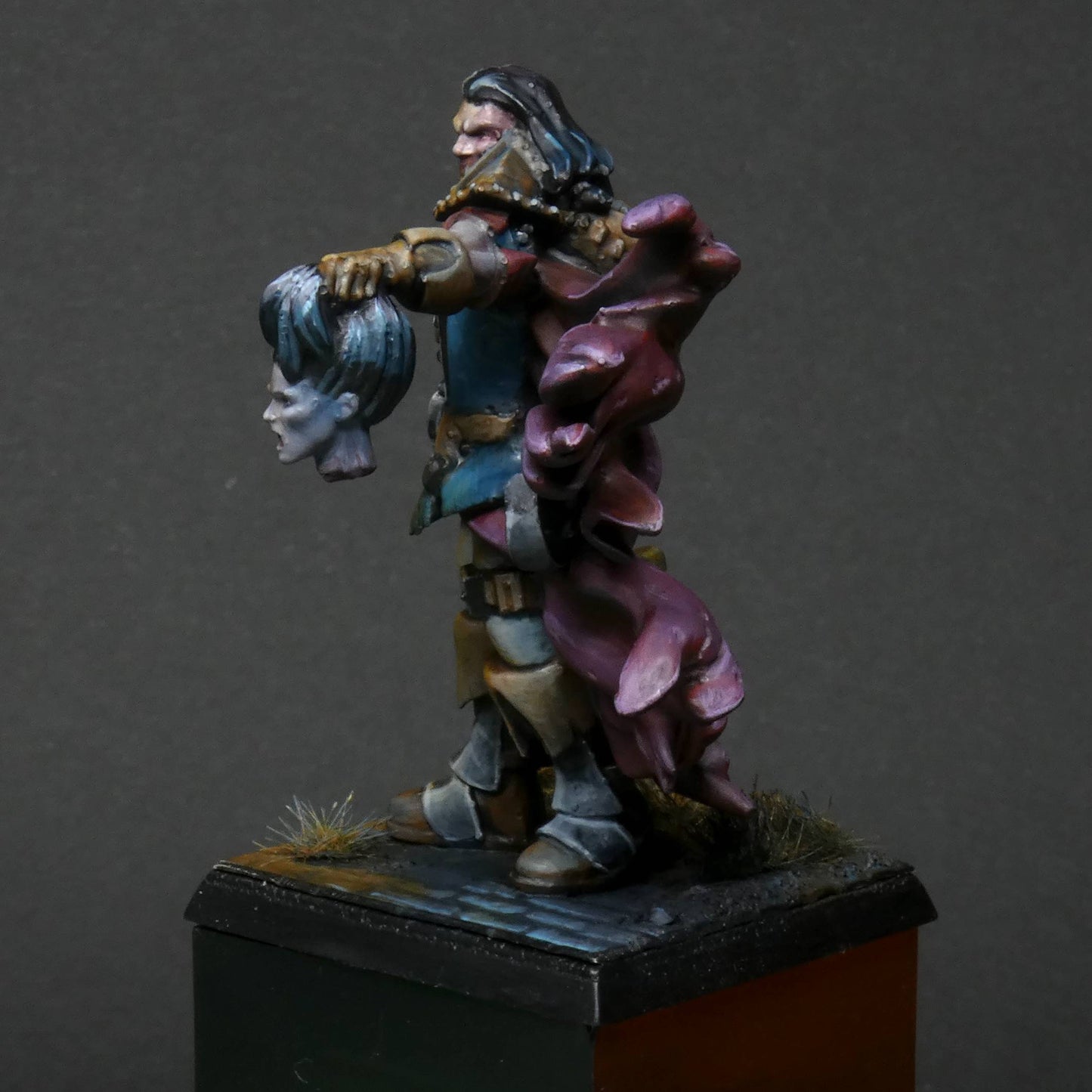 a 32mm scale miniature of Cristof Witchbane, a rugged witch hunter wielding a flaming torch and a severed witch's head.  The model is viewed painted beautifully with excellent lighting effects from the fire of the torch. 