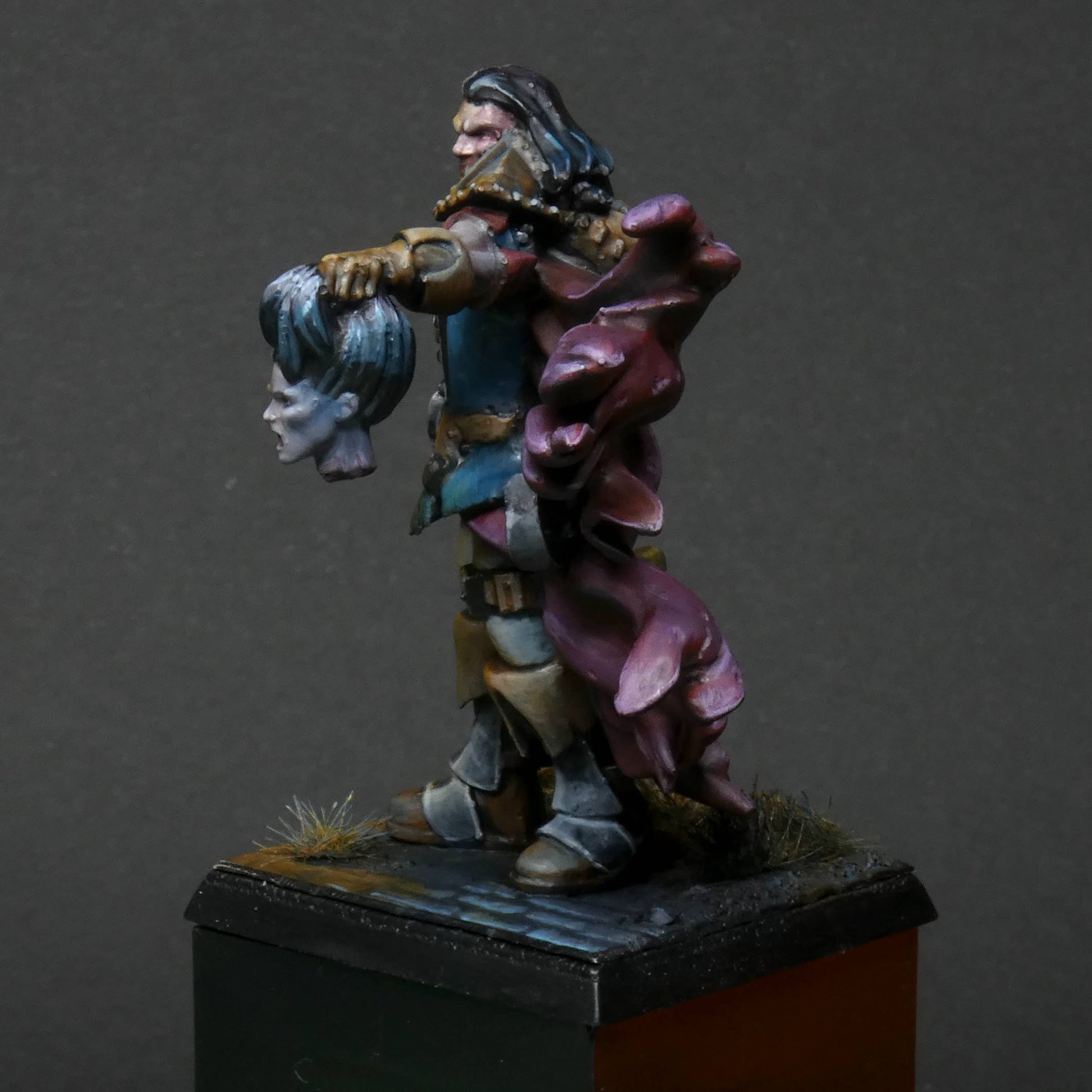 a 32mm scale miniature of Cristof Witchbane, a rugged witch hunter wielding a flaming torch and a severed witch's head.  The model is viewed painted beautifully with excellent lighting effects from the fire of the torch. 