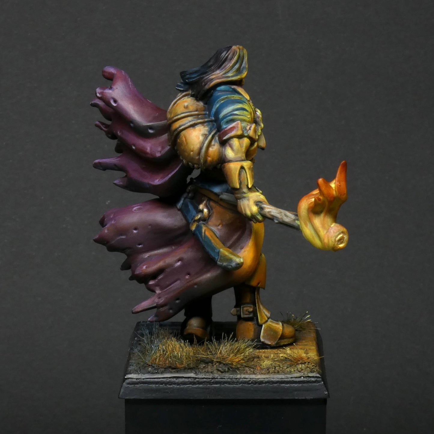 a right side view of 32mm scale miniature of Cristof Witchbane, a rugged witch hunter wielding a flaming torch and a severed witch's head.  The model is viewed painted beautifully with excellent lighting effects from the fire of the torch. 